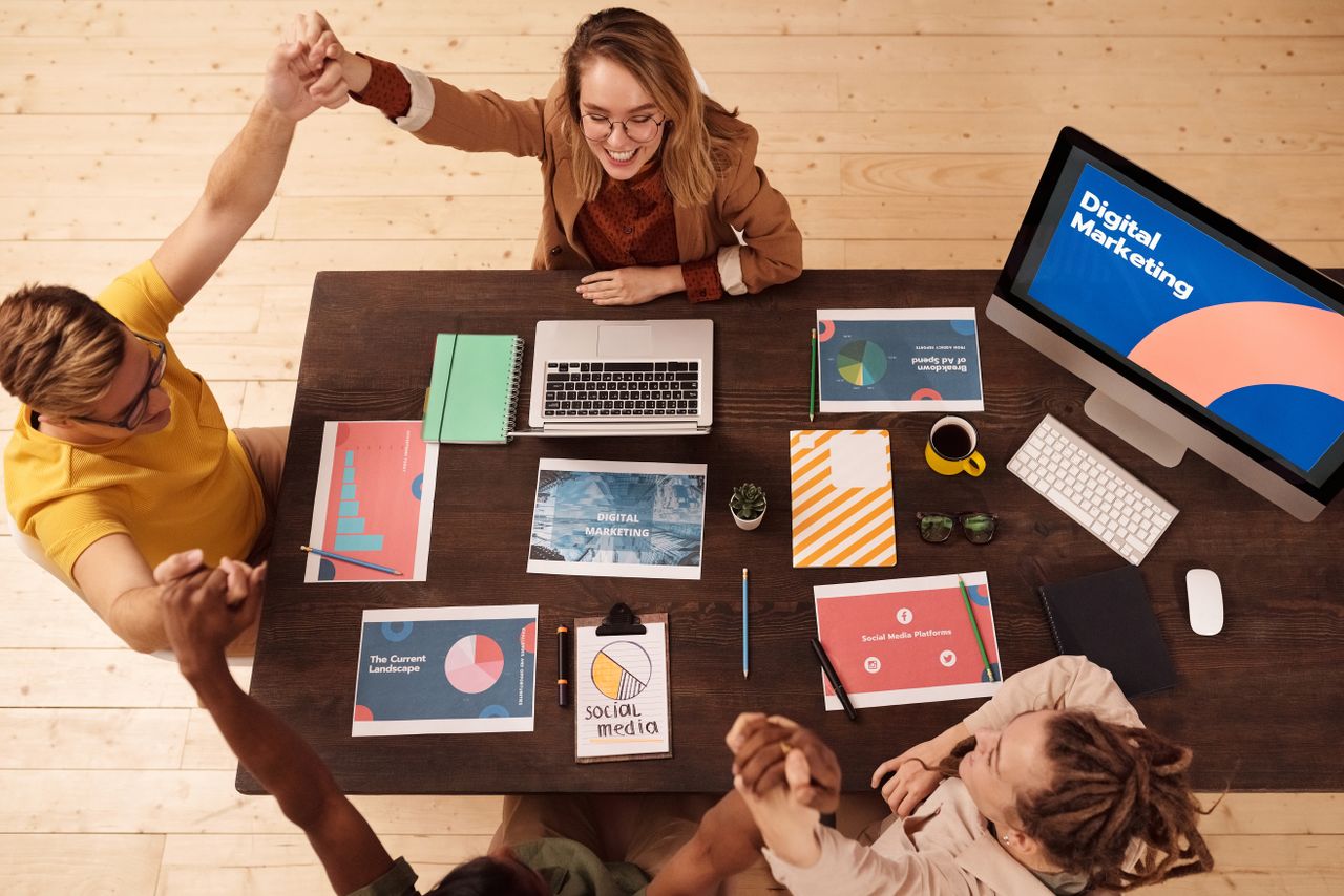 Coworkers celebrate a win in a modern digital marketing office, working together in a collaborative atmosphere.